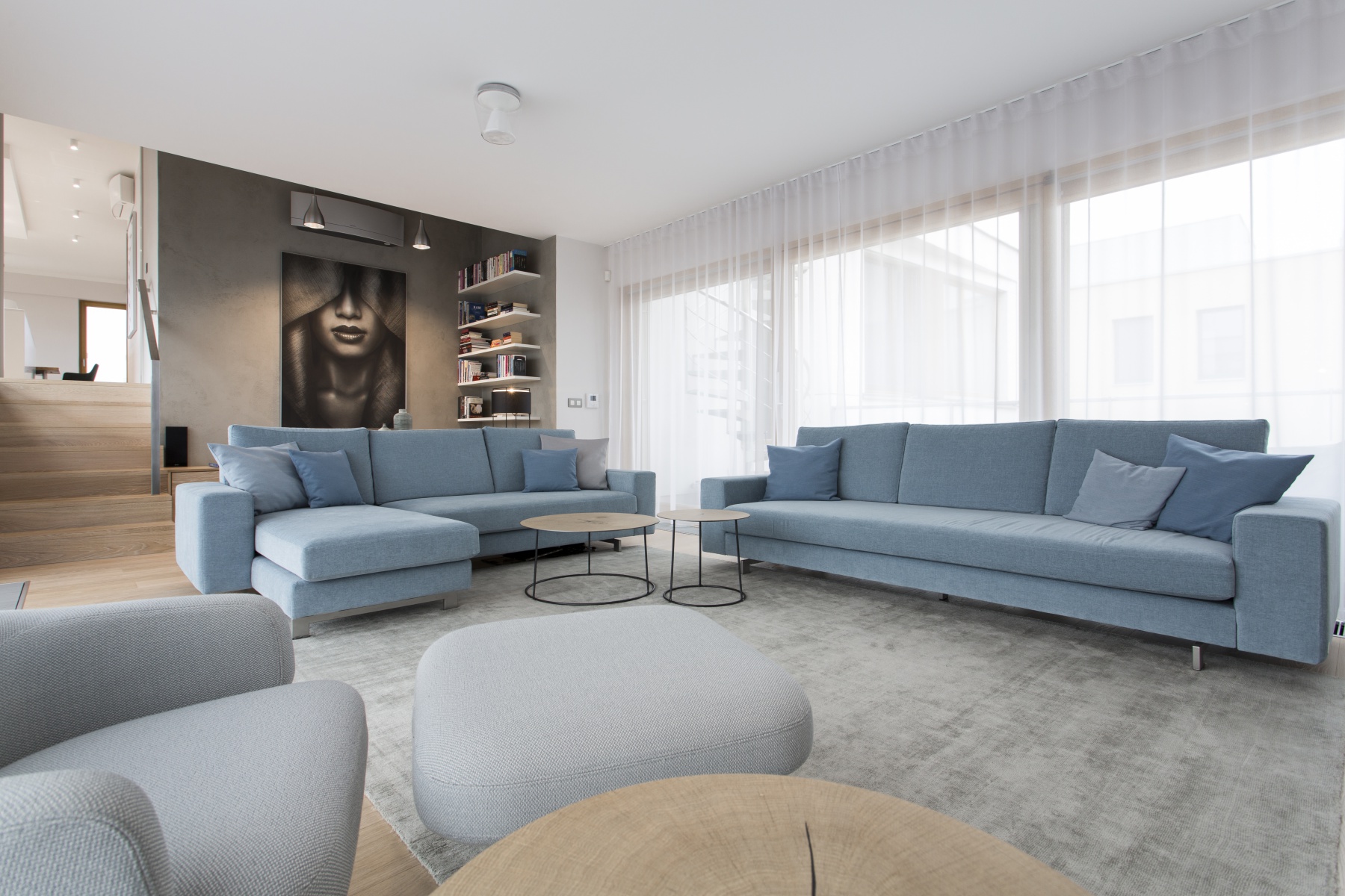 Obývací pokoj s modrou sedačkou a velkým oknem - Ambience Design.cz